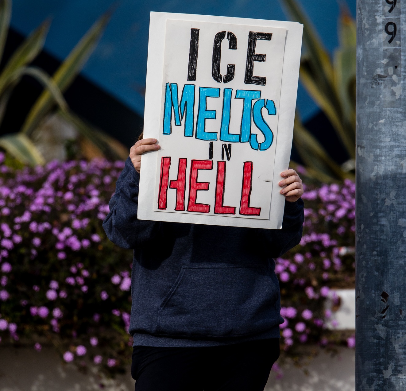 Protester with sign, ICE Melts in Hell