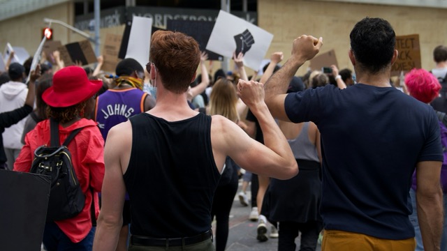Photo of the backs of protestors holding up raised fists